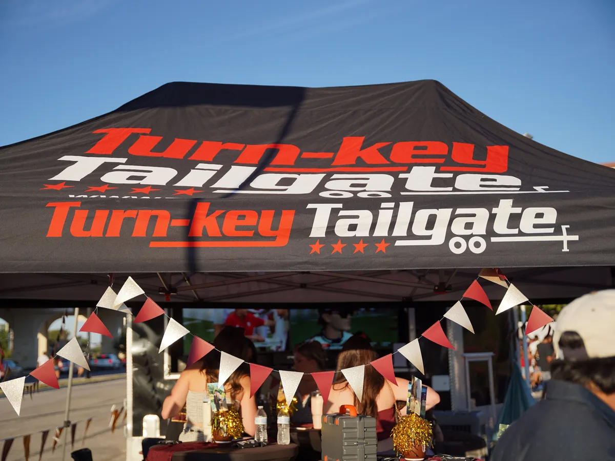 Turn-Key Tailgate branded game-day tent from Turnkey Tents & Events, with pennant banners and guests underneath