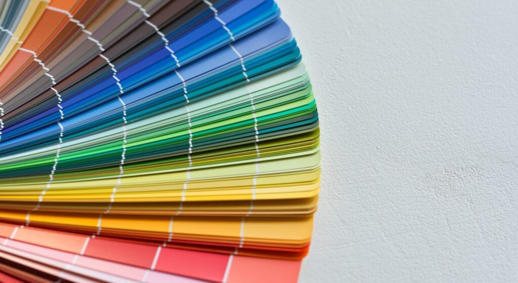 A fan deck of paint color swatches spread open on a white table, used to choose brand colors during a rebrand